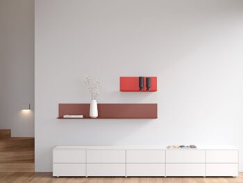 Minimalistisches Wohnzimmer mit einem Interlübke Sideboard, weißen Schränken, einem roten Schweberegal mit einer weißen Vase mit Zweigen und einer roten Wandbox mit zwei schwarzen Tassen vor einer hellgrauen Wand.