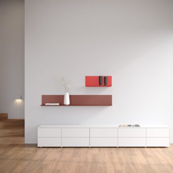 Minimalistisches Wohnzimmer mit einem Interlübke Sideboard, weißen Schränken, einem roten Schweberegal mit einer weißen Vase mit Zweigen und einer roten Wandbox mit zwei schwarzen Tassen vor einer hellgrauen Wand.