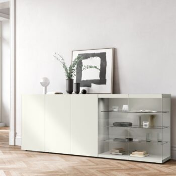 Minimalistisches Interlübke-Sideboard mit geschlossenen Schränken auf der linken Seite und Glasböden auf der rechten Seite für Bücher und Keramik; eine Vase, gerahmte Kunst und eine elegante Würfelleuchte sind darauf ausgestellt.