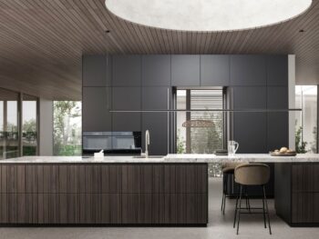 Leicht Bahia: Moderne Küche mit dunklen Schränken, holzgetäfelter Insel, Marmorarbeitsplatte und einem großen runden Oberlicht in der Holzdecke, mit minimalistischem Dekor und einem Barhocker.