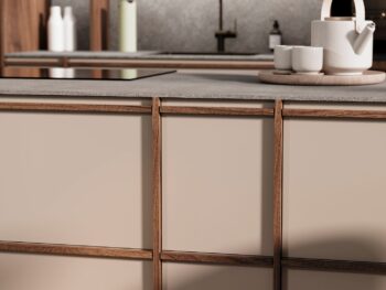 Leicht Küchen KYOTO - Nahaufnahme einer modernen Leicht Küchen KYOTO Kücheninsel mit beigen Paneelen und Holzverkleidung, mit Teekanne und Tassen auf einem Tablett im Hintergrund. Spüle und Seifenspender sind weiter hinten zu sehen.