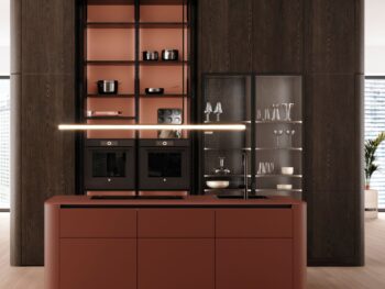 Leicht Küchen Rundwangen - Moderne Küche mit einer braunen Insel von Leicht Küchen und dunklen Holzschränken, mit Rundwangen-Details, offenen Regalen mit Kochgeschirr und einer Glasvitrine für Glaswaren in einem hellen Raum mit großen Fenstern.