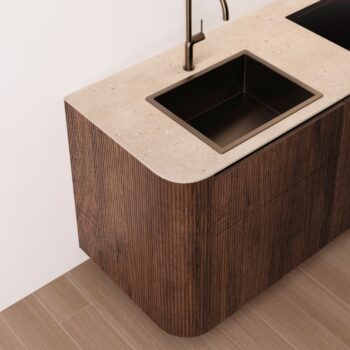 Leicht Küchen Rundwangen - Moderne Leicht Küchen Theke mit beiger Steinoberfläche, eingebautem rechteckigen Waschbecken, dunklem Wasserhahn, holzstrukturierten Schränken und eleganten Rundwangen-Details neben einem gefliesten Boden.