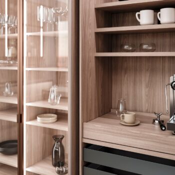 Leicht Küchen in der Trendfarbe Beige - In den hölzernen Regalen und Schränken von Leicht Küchen stehen Glaswaren, Keramiktassen, Teller und eine Kaffeemaschine. Einige Regale sind mit Glastüren abgedeckt, während andere offen bleiben. So entsteht eine aufgeräumte und elegante Küche, die an das raffinierte Design des Taj Mahal erinnert.