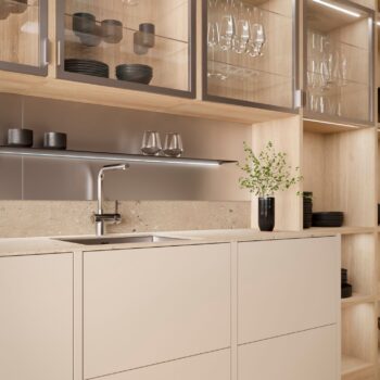 Leicht Küchen in der Trendfarbe Beige - Moderne Küche von Leicht Küchen mit hellen Schränken, einer Edelstahlspüle, Oberschränken mit Glasfront und einer Topfpflanze. Schwarzes Geschirr und Gläser sind ordentlich angeordnet und verleihen der Küche eine vom Taj Mahal inspirierte Eleganz.