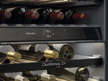 Der elegante Miele-Weinkühlschrank KWTUS 7196 E ist ein Weinkühler mit Flaschenregalen, die mit Merlot 22 und Chardonnay 24 beschriftet sind, und einer digitalen Temperaturanzeige von 18°C und 12°C.