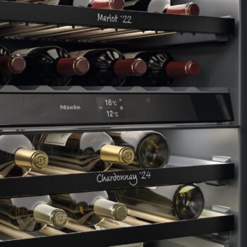 Der elegante Miele-Weinkühlschrank KWTUS 7196 E ist ein Weinkühler mit Flaschenregalen, die mit Merlot 22 und Chardonnay 24 beschriftet sind, und einer digitalen Temperaturanzeige von 18°C und 12°C.
