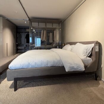 Ein ordentliches Polsterbett mit weißer Bettwäsche steht vor einem begehbaren Kleiderschrank mit Glasabdeckung, der dieses moderne, minimalistische Fulham-Schlafzimmer mit eleganten Molteni&C-Design-Elementen aufwertet.