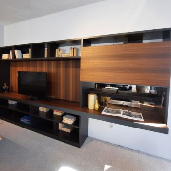 Moderne Molteni 505 Anbauwand mit Fernseher, Büchern und Dekorationsgegenständen sowie einem ausklappbaren Schreibtisch, auf dem offene Bücher liegen – das Ganze vor dem Hintergrund eines stilvollen Teppichbodens.