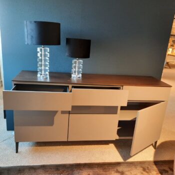 Ein modernes Molteni&C 505 Sideboard mit Holzplatte, zwei schwarzen Lampen, zwei teilweise geöffneten Schubladen und einer angelehnten Schranktür steht elegant vor einer blauen Wand.