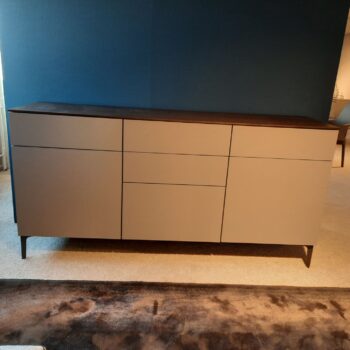 Ein modernes 505-Sideboard von Molteni&C verfügt über eine dunkle Oberseite, helle Schranktüren und Schubladen und steht auf vier schlanken Beinen vor einer blauen Wand.