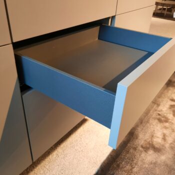 Eine Nahaufnahme eines modernen, mattierten Molteni&C 505 Sideboards mit einer teilweise geöffneten blauen Innenschublade, die den Blick auf ein leeres Inneres freigibt.