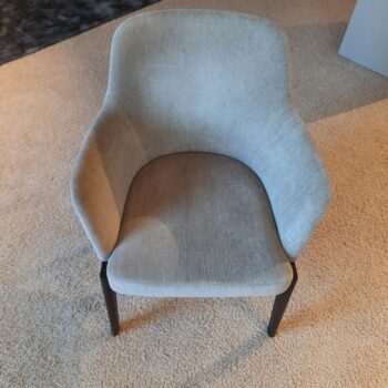 Ein hellgrau gepolsterter Sessel aus dem Chelsea Stühle Set von Molteni&C mit geschwungener Rückenlehne und dunklen Holzbeinen auf beigem Teppichboden.