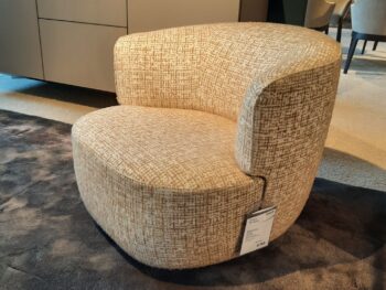 Ein moderner, beige gepolsterter Elain-Drehsessel von Molteni&C mit geschwungener Rückenlehne steht auf einem dunklen Teppich in einem Ausstellungsraum, an seinem Fuß ist ein Preisschild befestigt.