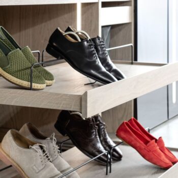 Ein Holzregal von Sudbrock im Kleiderschrank, auf dem eine Kollektion von Herrenschuhen ausgestellt ist, darunter Loafer und Oxfords in verschiedenen Farben.
