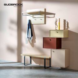 Modernes Flurmöbel-Set aus der „Modo Garderobe“-Kollektion von Sudbrock, bestehend aus Wandhaken, einem Glasregal, einer schlichten Bank und vier geometrischen Aufbewahrungsschränken in neutralen und warmen Farbtönen. Ein Schal, eine Figur und Kerzenständer runden das stilvolle Gesamtbild ab.