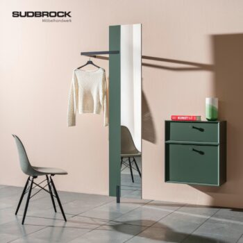 Minimalistischer Flur mit einem grünen Wandschrank von Sudbrock, einem vertikalen Spiegel, einem Kleiderbügel mit Pullover, einem Stuhl und einem rotem Buch als Dekoration – ein raffinierter Akzent von Modo Garderobe für moderne Innenräume.