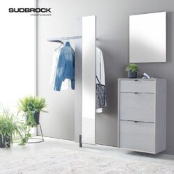 Moderner Eingangsbereich mit dem eleganten Kleiderschrank „Modo Garderobe“ von Sudbrock, ausgestattet mit einem hohen Spiegel, einer Kleiderstange, einer Kommode, einer kleinen Pflanze, einem Wandspiegel und einer großen Topfpflanze auf dem Boden. Das SUD-BROCK-Logo ist elegant an der Wand angebracht.