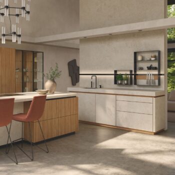 Moderne Küche mit hellen Holzschränken von Team7 Küche, einer großen Insel mit zwei orangefarbenen Stühlen, offenen Regalen und minimalistischem Dekor, alles erhellt von natürlichem Licht aus großen Fenstern - perfekt, um echt.zeit-Momente zu genießen.