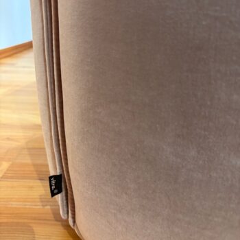 Nahaufnahme eines beigen, gepolsterten Vitra Mariposa Club-Sessels mit sichtbarem Vitra-Etikett, der auf einem Holzboden steht.