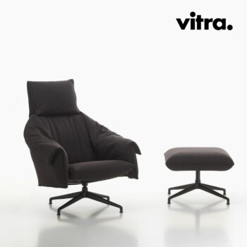 Ein schwarzer, gepolsterter Vitra-Lounge-Sessel mit passendem Hocker, beide auf schwarzen Drehgestellen, vor einem schlichten weißen Hintergrund. Vitra-Logo in der oberen rechten Ecke.