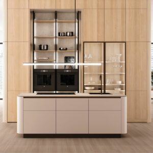 Moderne Architekturküche von Möbel Braum mit zentraler Insel, eingebauten LEICHT-Backöfen, offenen Regalen mit Kochgeschirr, einer Glasvitrine für Gläser und einer hellen Holzverkleidung.