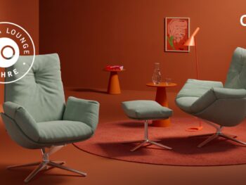 Zwei grüne Cordia Lounge Sessel mit passender Ottomane stehen auf einem orangefarbenen Teppich in einem modernen, orangefarbenen Raum und feiern Perfektion und Jubiläum mit 