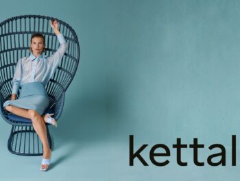 Eine Frau sitzt auf einem großen, ikonischen Korbsessel von Kettal vor einem blauen Hintergrund. Das Wort Kettal und die Zahl 60 erscheinen auf der rechten Seite dieses von Outdoormöbel inspirierten Bildes.