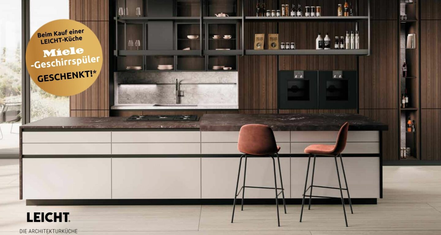 Moderne Küche mit großer Insel, zwei Barhockern, offenen Regalen, dunkler Arbeitsplatte und Einbaugeräten von LEICHT Architekturküchen; auf dem Bild ist ein Werbeaufkleber für Möbel Braum zu sehen.