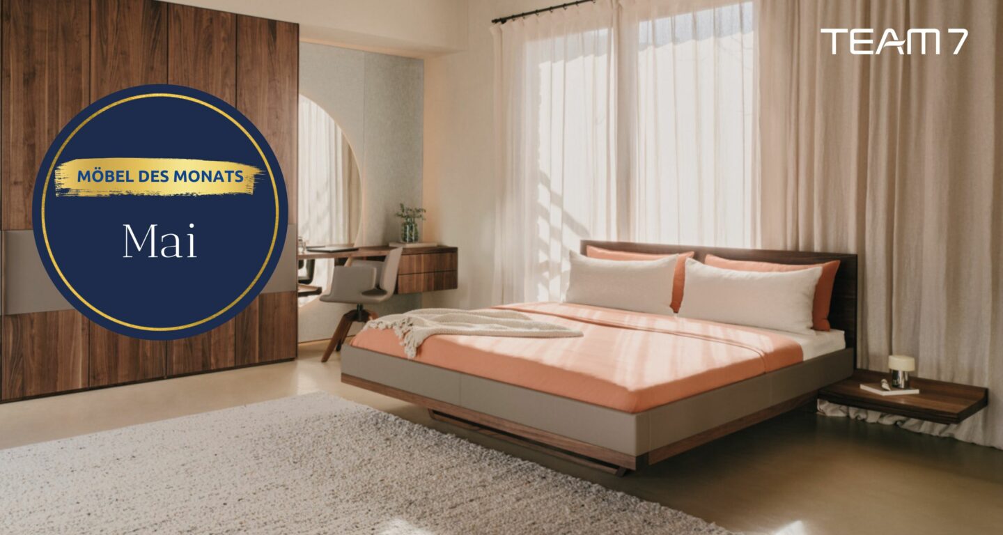 Modernes Schlafzimmer mit einem Holzbett, einem Schreibtisch und Beistelltischen, einem großen Fenster und Vorhängen - und dem Text Möbelhaus Bad Homburg und TEAM 7, der über das Bild gelegt wurde.