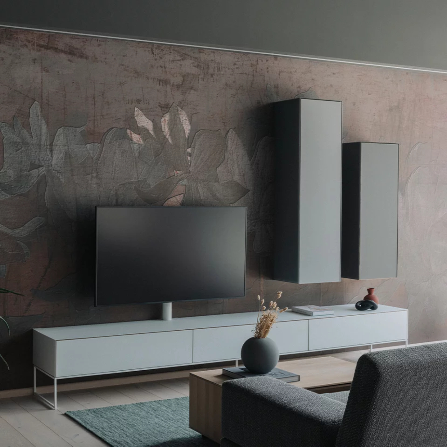 Modernes Wohnzimmer mit einer Team 7 cubus pure Wohnwand, mit einem Flachbildfernseher auf einem niedrigen weißen Schrank, zwei hohen Hängeschränken, einem grauen Sofa und einem minimalistischen Couchtisch mit einer Vase und Trockenblumen. Modernes Wohnzimmer mit einer Team 7 cubus pure Wohnwand, mit einem Flachbildfernseher auf einem niedrigen weißen Schrank, zwei hohen Hängeschränken, einem grauen Sofa und einem minimalistischen Couchtisch mit einer Vase und Trockenblumen.