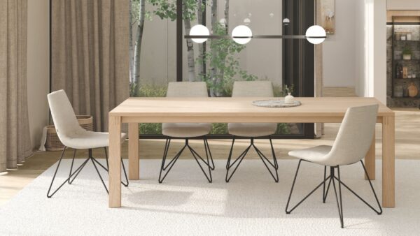 Modernes Esszimmer mit einem TEAM 7 Light Holztisch, vier beigefarbenen Stühlen mit schwarzen Metallbeinen, einem runden Tablett und großen Fenstern, die den Blick auf die Bäume im Freien freigeben - Teil der Kollektion Schnellliefersortiment Essentials.