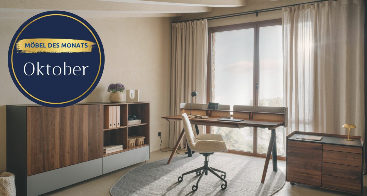 Modernes Home Office mit Holzmöbeln, Schreibtisch, Drehstuhl, Regalen und einem großen Fenster mit Vorhängen. Auf einer runden Plakette steht Möbel des Monats Oktober - entdecken Sie exklusives Design im Möbelhaus Bad Homburg.