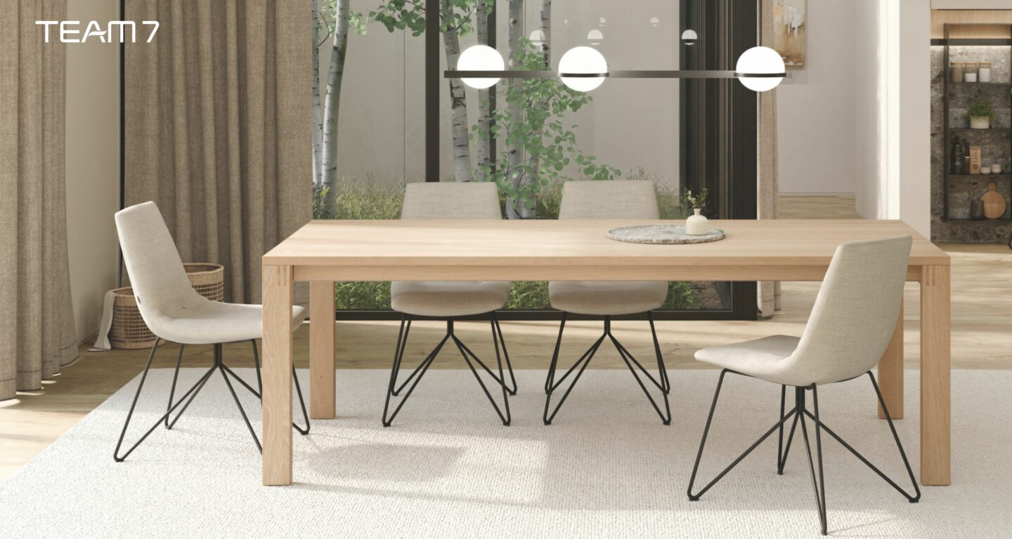 Ein modernes Esszimmer mit einem hellen Holztisch vom Möbelhaus Bad Homburg, vier gepolsterten Stühlen auf schwarzen Metallbeinen, neutralem Dekor, großen Fenstern und Pendelleuchten darüber. Ein modernes Esszimmer mit einem hellen Holztisch vom Möbelhaus Bad Homburg, vier gepolsterten Stühlen auf schwarzen Metallbeinen, neutralem Dekor, großen Fenstern und Pendelleuchten darüber.