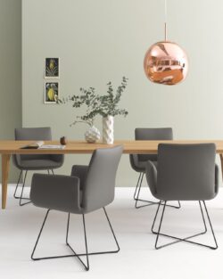 Modernes Esszimmer mit einem COR Jalis Stuhl um einen Holztisch, sechs grauen Stühlen mit Metallbeinen, einer kupfernen Pendelleuchte, einer Vase mit Grünzeug und zwei kleinen Wandbildern - perfekt für jede Gelegenheit oder Aktion.